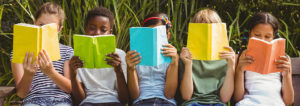 Children sitting in row and reading books at the park